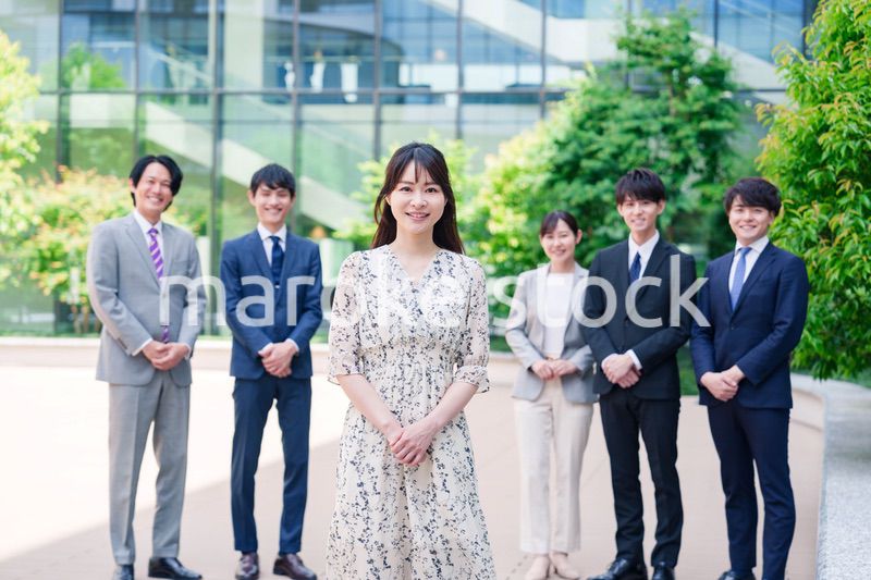 オフィス街に立つ若い女性キャリアウーマンとスタッフ