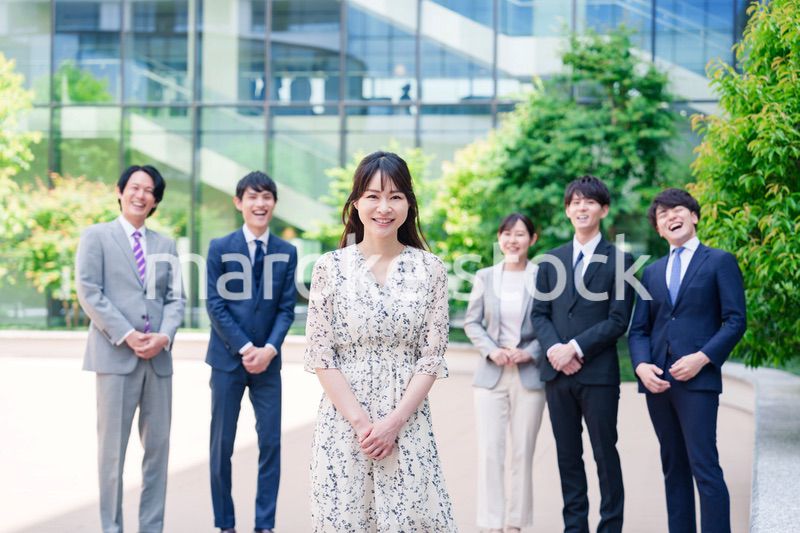 オフィス街に立つ若い女性キャリアウーマンとスタッフ