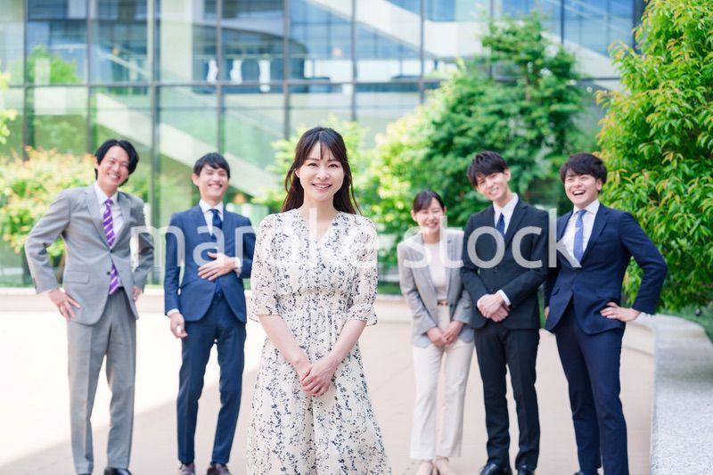 オフィス街に立つ若い女性キャリアウーマンとスタッフ