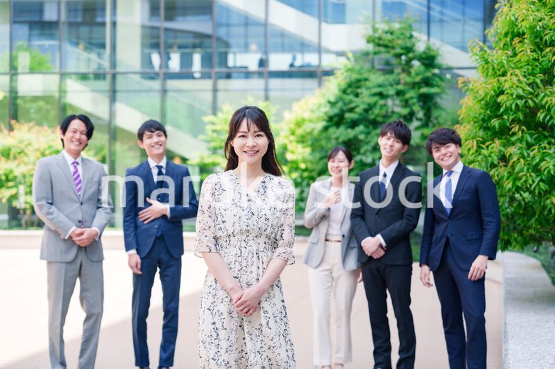 オフィス街に立つ若い女性キャリアウーマンとスタッフ