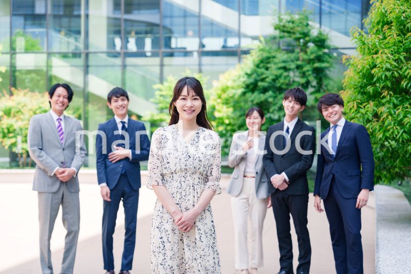 オフィス街に立つ若い女性キャリアウーマンとスタッフ