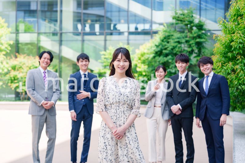 オフィス街に立つ若い女性キャリアウーマンとスタッフ