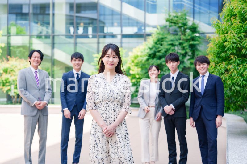 オフィス街に立つ若い女性キャリアウーマンとスタッフ