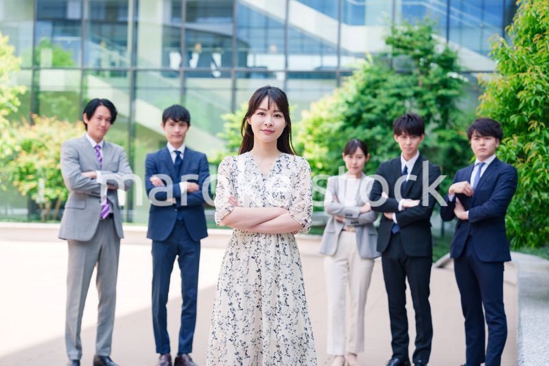 オフィス街に立つ若い女性キャリアウーマンとスタッフ