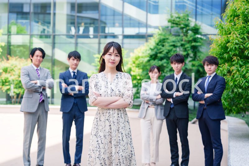 オフィス街に立つ若い女性キャリアウーマンとスタッフ