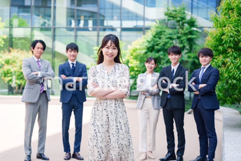 オフィス街に立つ若い女性キャリアウーマンとスタッフ