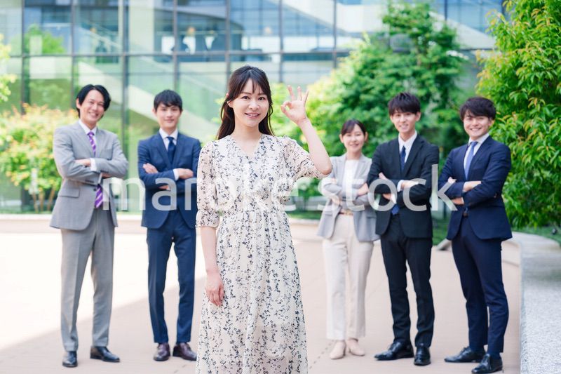 オフィス街に立つ若い女性キャリアウーマンとスタッフ