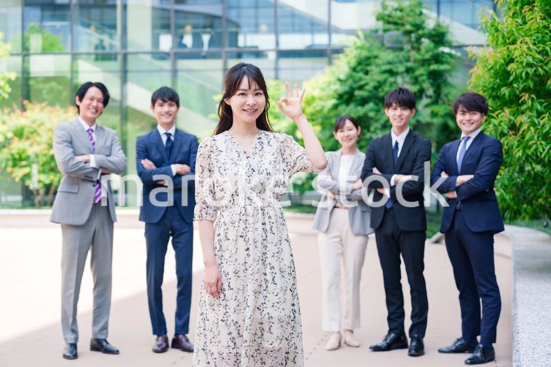 オフィス街に立つ若い女性キャリアウーマンとスタッフ