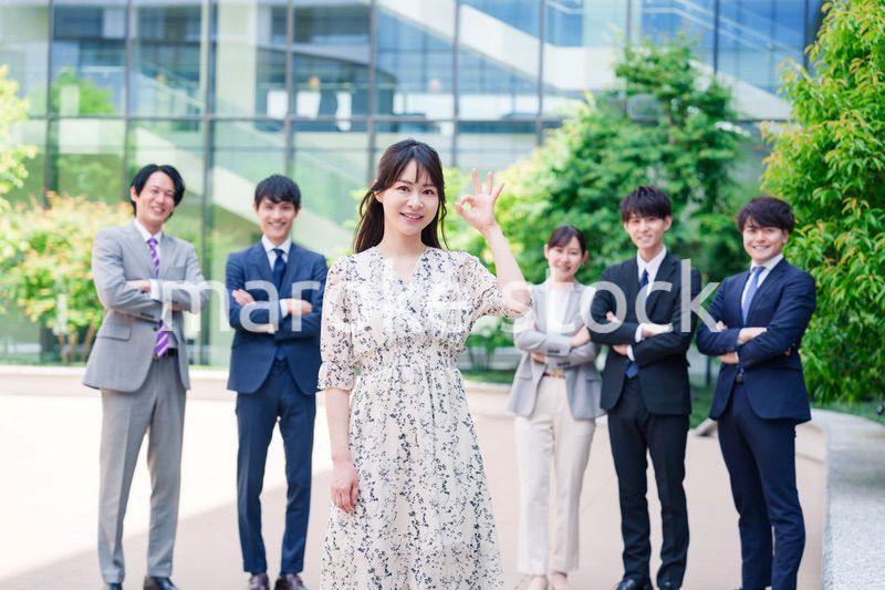 オフィス街に立つ若い女性キャリアウーマンとスタッフ