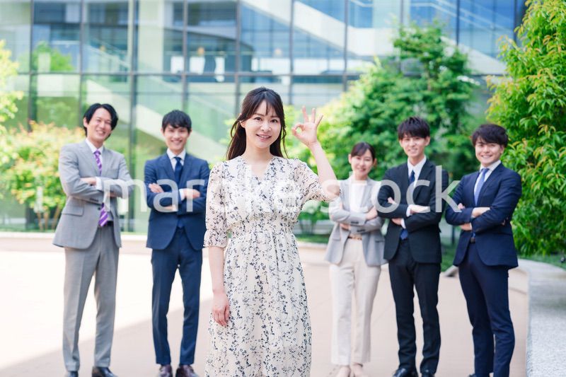 オフィス街に立つ若い女性キャリアウーマンとスタッフ