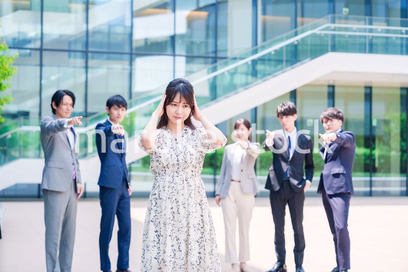 同僚に責められて頭を抱える女性のビジネスパーソン