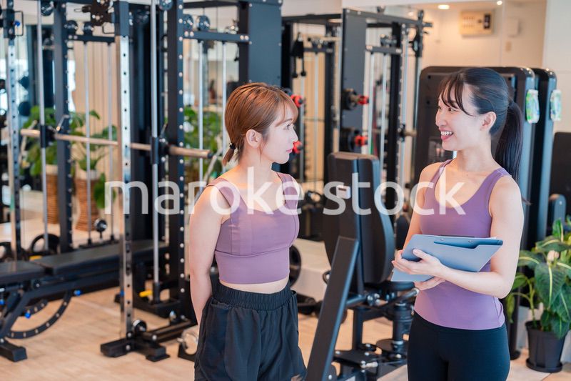 女性トレーナーからの指導を受けて筋トレをする女性