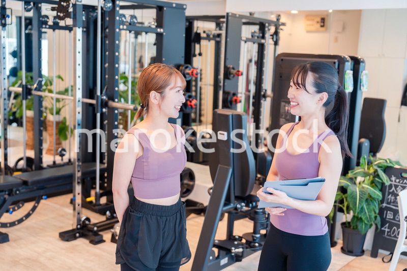 女性トレーナーからの指導を受けて筋トレをする女性