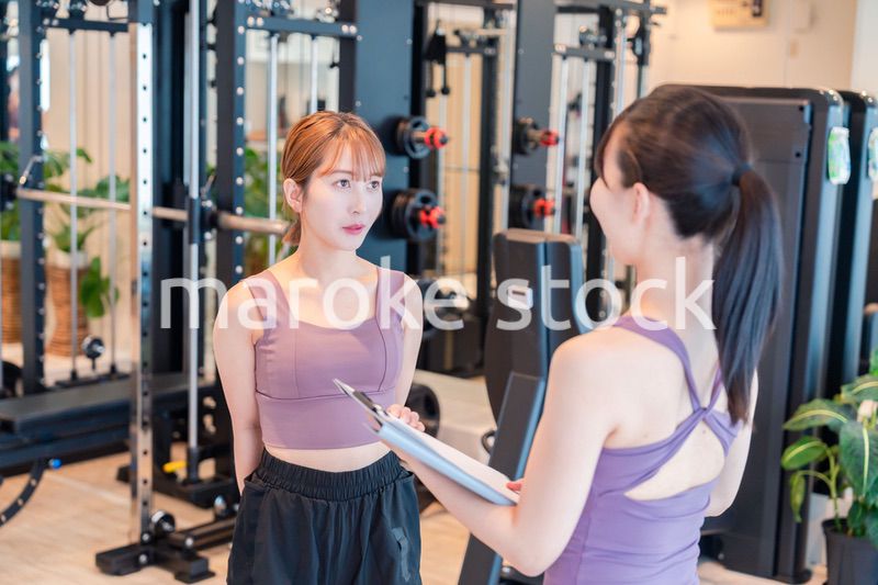 女性トレーナーからの指導を受けて筋トレをする女性