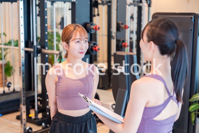 女性トレーナーからの指導を受けて筋トレをする女性