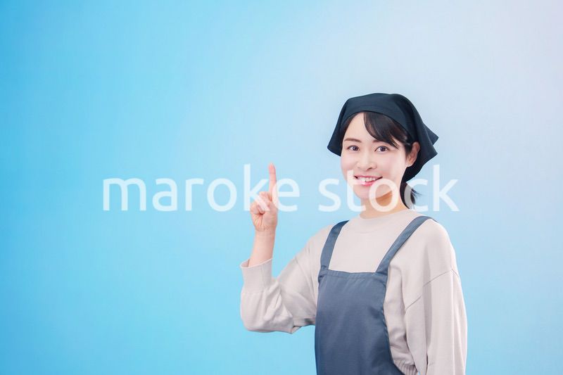 エプロンを着た調理師の若い女性（水色背景）
