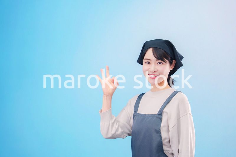 エプロンを着た調理師の若い女性（水色背景）