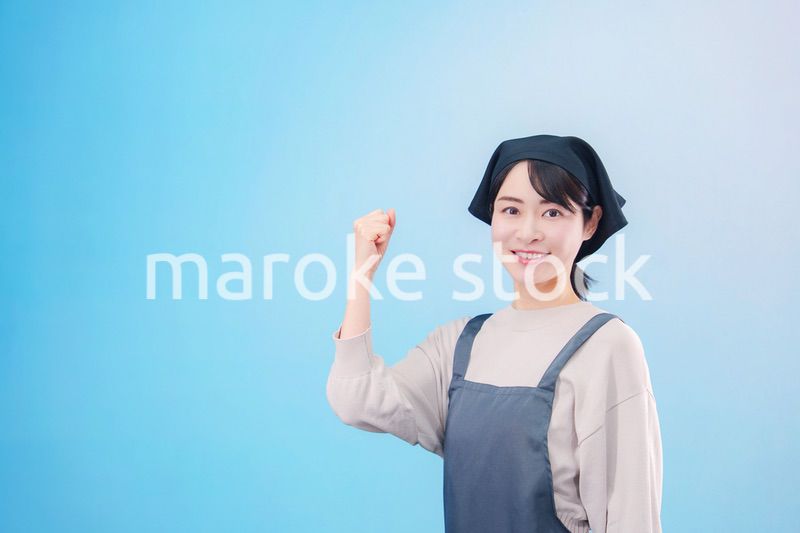 エプロンを着た調理師の若い女性（水色背景）