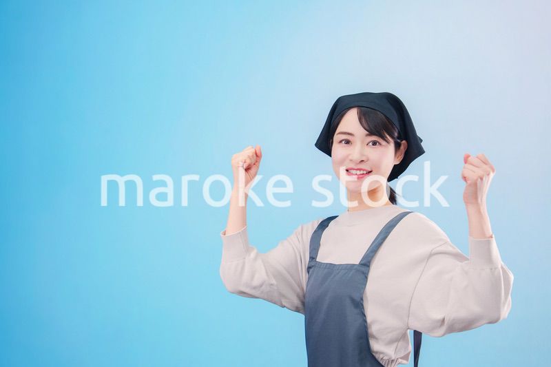 エプロンを着た調理師の若い女性（水色背景）