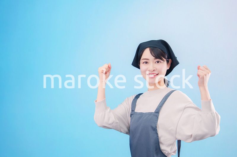エプロンを着た調理師の若い女性（水色背景）