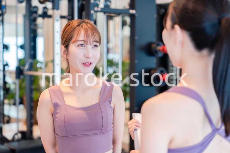 女性トレーナーからの指導を受けて筋トレをする女性