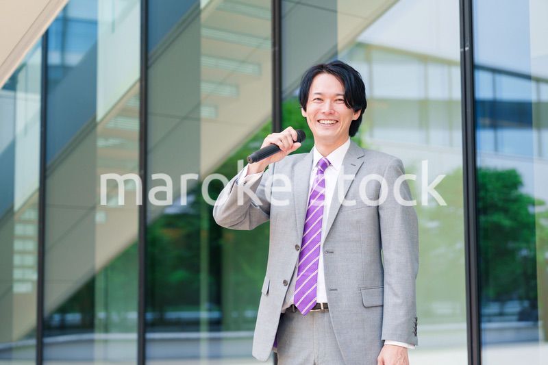 マイクを使って街なかで演説をするスーツを着た男性