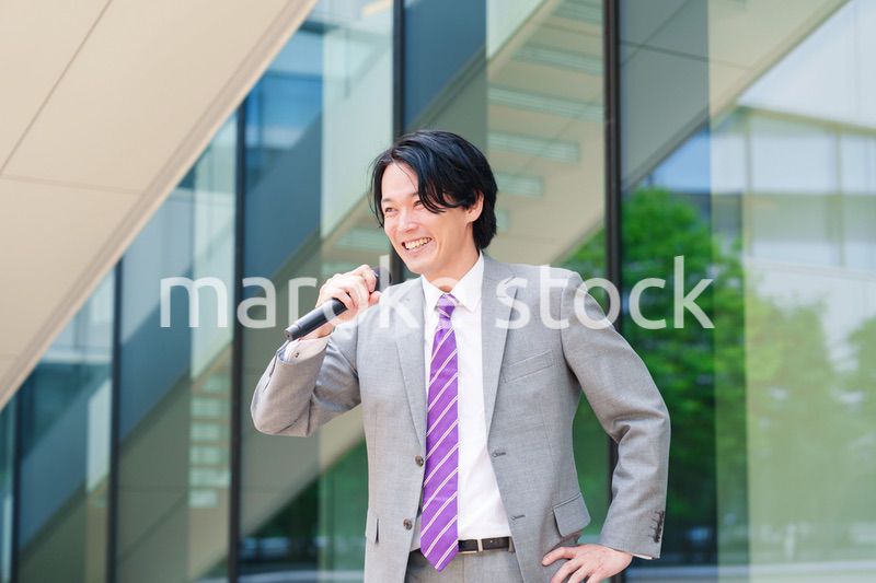 マイクを使って街なかで演説をするスーツを着た男性