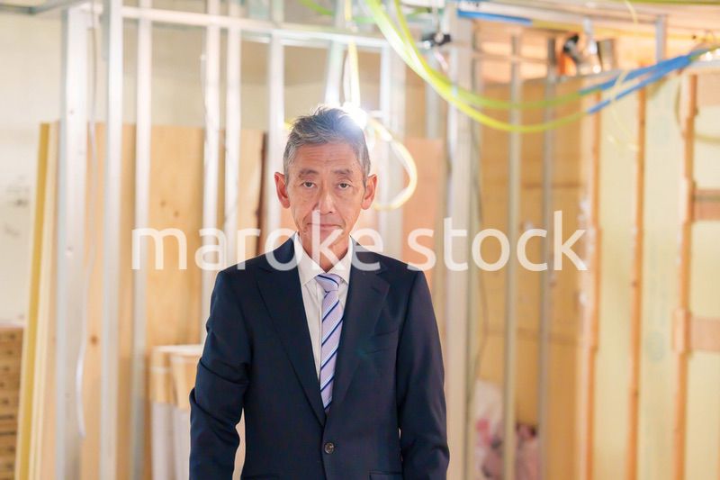 スーツ姿で現場に立つ工務店の男性経営者