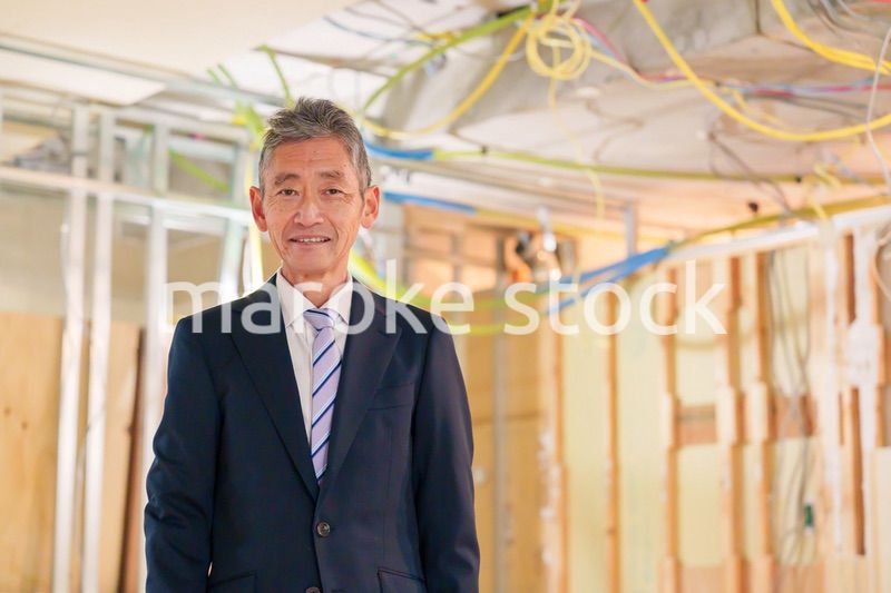スーツ姿で現場に立つ工務店の男性経営者