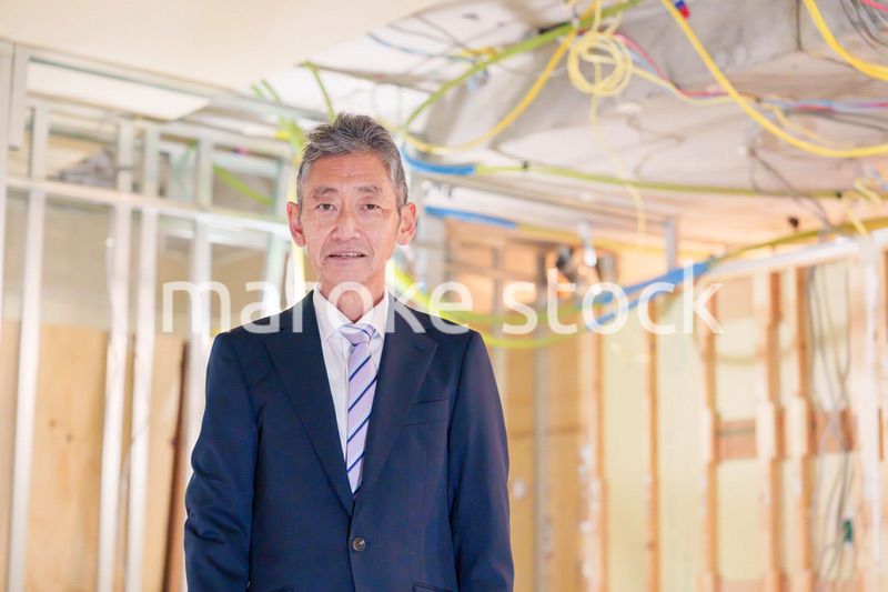 スーツ姿で現場に立つ工務店の男性経営者