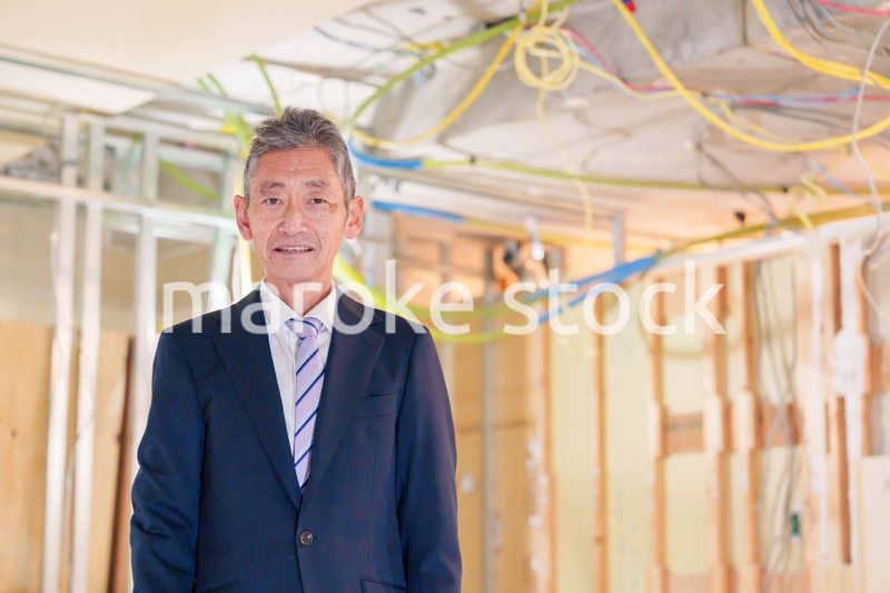スーツ姿で現場に立つ工務店の男性経営者
