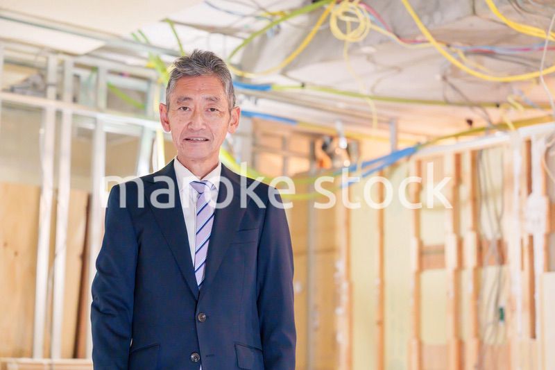 スーツ姿で現場に立つ工務店の男性経営者