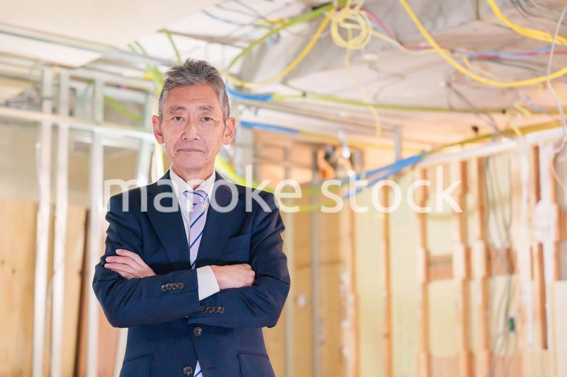 スーツ姿で現場に立つ工務店の男性経営者