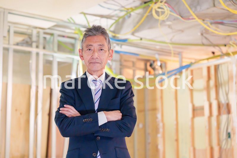 スーツ姿で現場に立つ工務店の男性経営者