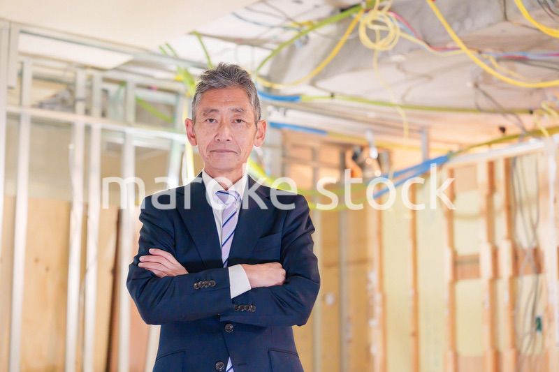 スーツ姿で現場に立つ工務店の男性経営者