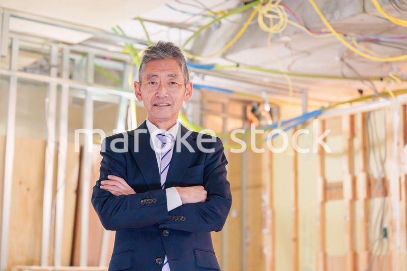 スーツ姿で現場に立つ工務店の男性経営者