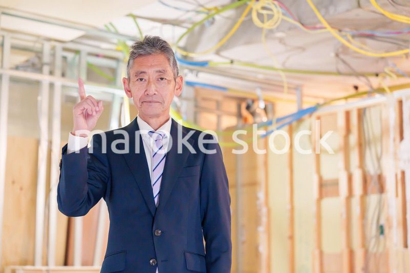 スーツ姿で現場に立つ工務店の男性経営者