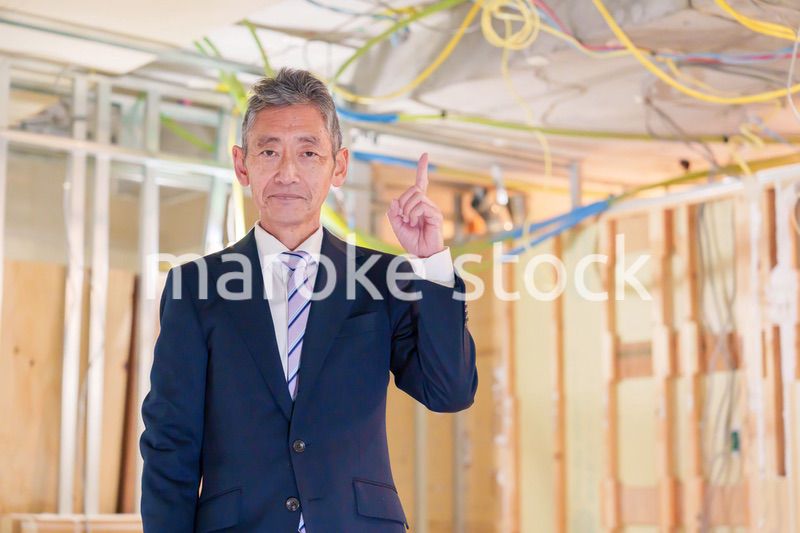 スーツ姿で現場に立つ工務店の男性経営者