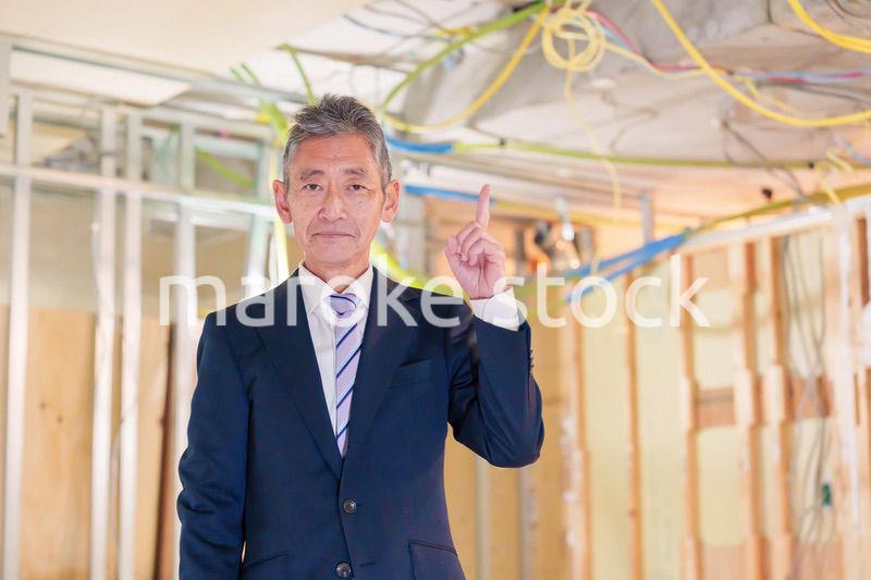 スーツ姿で現場に立つ工務店の男性経営者
