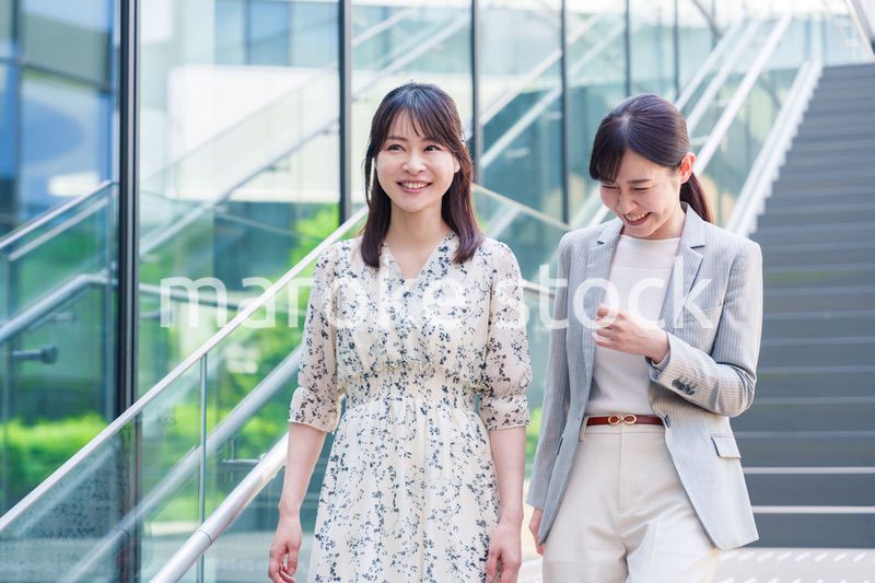 楽しく話しながらオフィスの中を歩く女性ビジネスパーソン