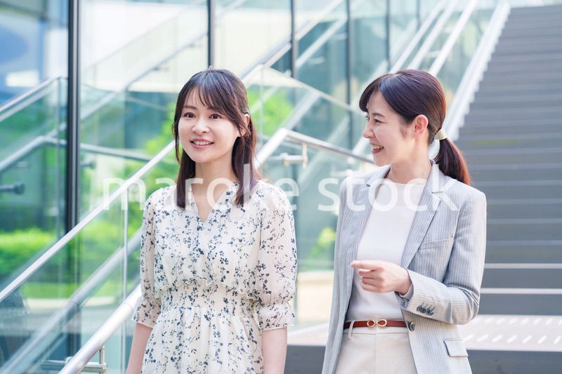 楽しく話しながらオフィスの中を歩く女性ビジネスパーソン