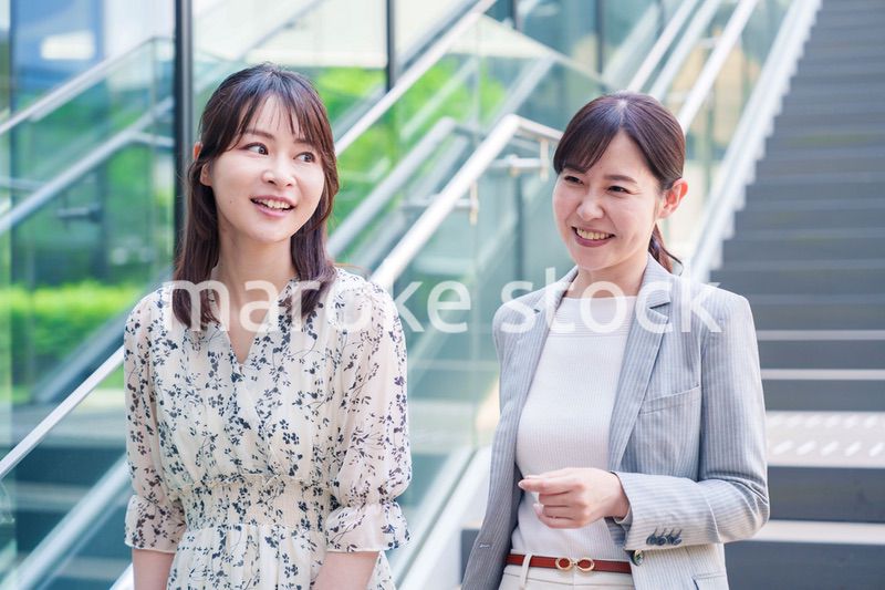 楽しく話しながらオフィスの中を歩く女性ビジネスパーソン