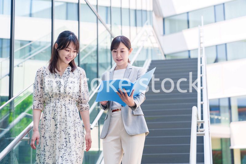 楽しく話しながらオフィスの中を歩く女性ビジネスパーソン