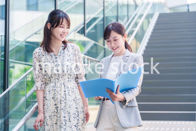 楽しく話しながらオフィスの中を歩く女性ビジネスパーソン