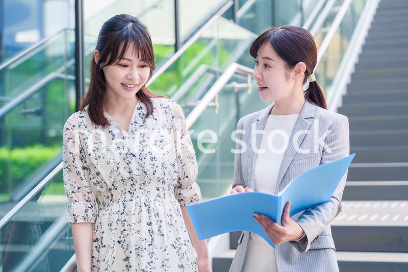 楽しく話しながらオフィスの中を歩く女性ビジネスパーソン