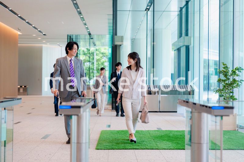オフィスのエントランスを通るビジネスパーソン