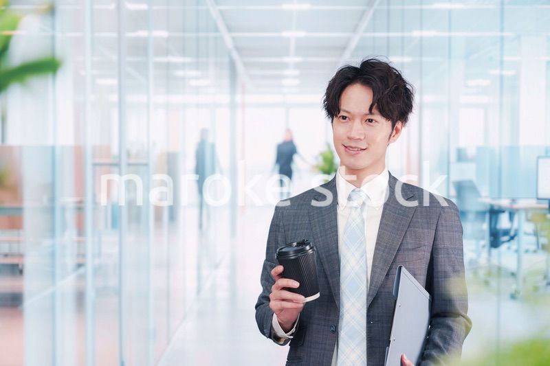 オフィスで紙カップのコーヒーを持って歩くビジネスマン