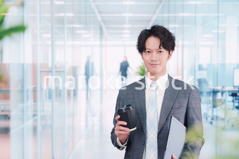 オフィスで紙カップのコーヒーを持って歩くビジネスマン