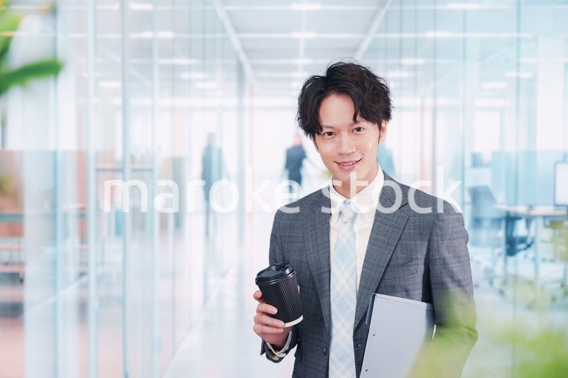オフィスで紙カップのコーヒーを持って歩くビジネスマン