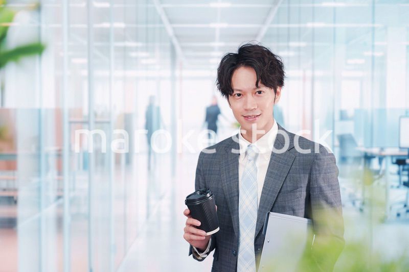 オフィスで紙カップのコーヒーを持って歩くビジネスマン